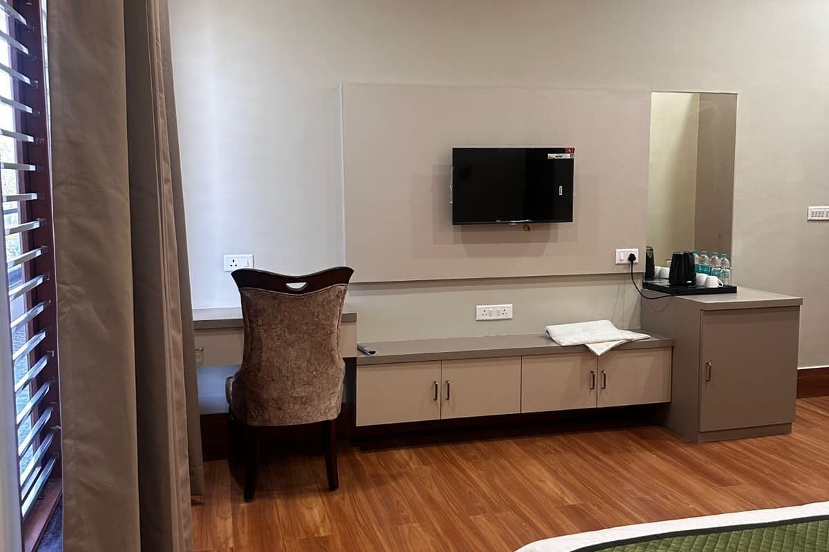 A hotel room with a bed, a desk with a television, a chair, and a cabinet.