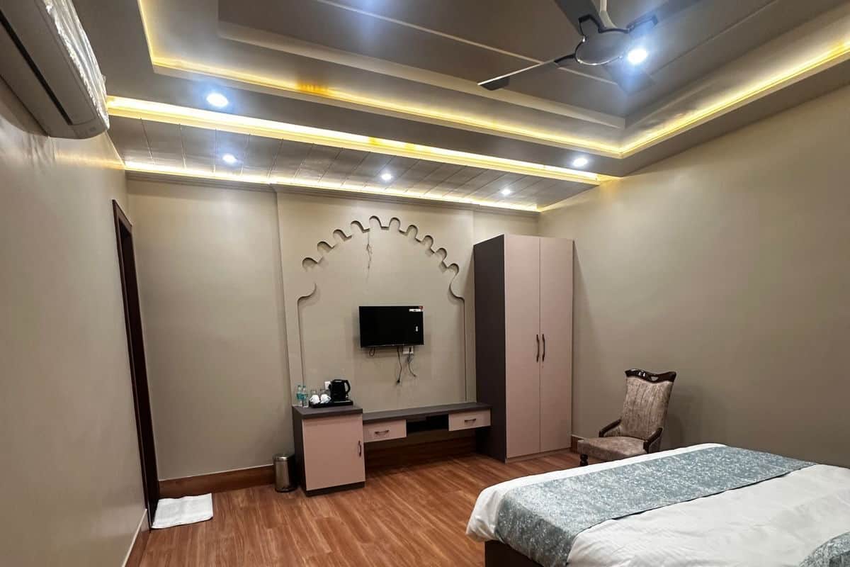 A bedroom with a bed, a TV, a wardrobe, a chair, and a desk.
