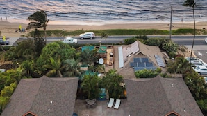 Uma propriedade à beira-mar com piscina, espreguiçadeiras e vista para o oceano ao pôr do sol.