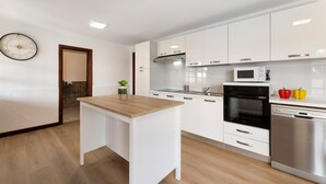 A modern kitchen with white cabinets, a wooden countertop, a built-in oven, a microwave, and a dishwasher. - Villa Careva Suites 2 - VipVipVillas (Costa Teguise)