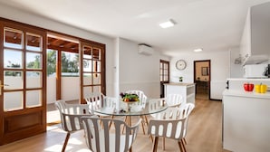 A modern kitchen with white cabinets and a dining area with a glass table and white chairs. - Villa Careva Suites 2 - VipVipVillas (Costa Teguise)