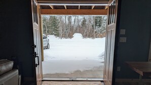 A doorway leading to a snowy outdoor area with a car parked outside.