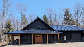 A rustic barn-style building with a covered porch, large windows, and a garage.