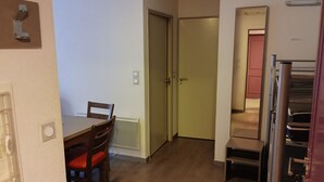 Una cuina compacta amb zona de menjador, nevera i una porta que condueix a una altra habitació.