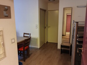 Eine kompakte Küche mit Essbereich, einem Kühlschrank und einer Tür zu einem weiteren Raum.