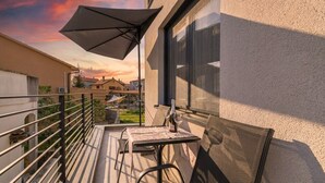 A balcony with a table, chairs, and a bottle of wine. - Cocaletto Villa / Bohemia Apartment 6 (Rovinj)