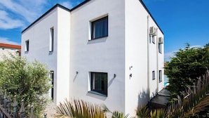 Un bâtiment moderne, blanc, à deux étages, doté d’un toit plat, de fenêtres rectangulaires et d’un petit balcon.