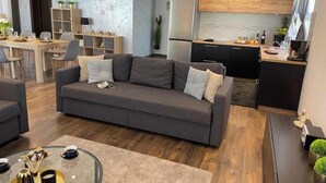 Un salon moderne avec un canapé gris, une table basse et un coin repas comprenant une table et des chaises en bois.