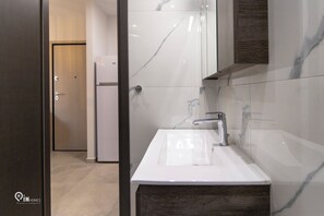 A modern bathroom with a white sink, a mirror, and a wooden cabinet. - Apollon - Premium Studio Near Metro Athens (Athina)