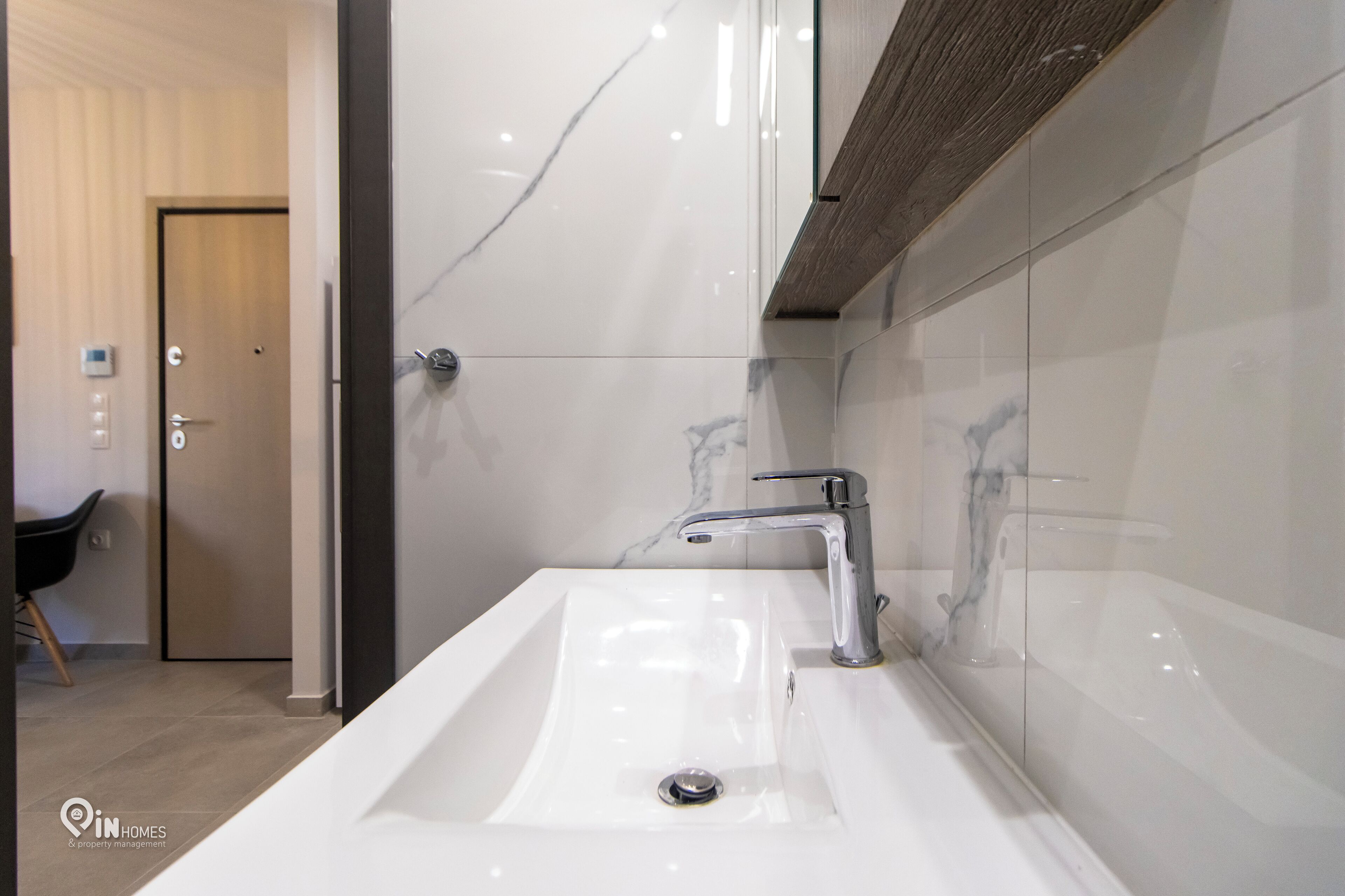 A modern bathroom with a large white sink, a chrome faucet, and a wooden ceiling.
