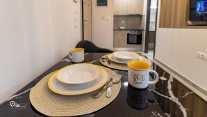 Un comedor con una mesa dispuesta para cuatro, incluyendo platos, cubiertos y tazas de café.