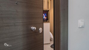 Un baño moderno con puerta de madera, lavabo blanco y zona de ducha visible.