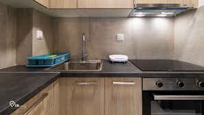 Una cocina moderna con armarios de madera, un lavamanos de acero inoxidable, horno empotrado y una estufa compacta.