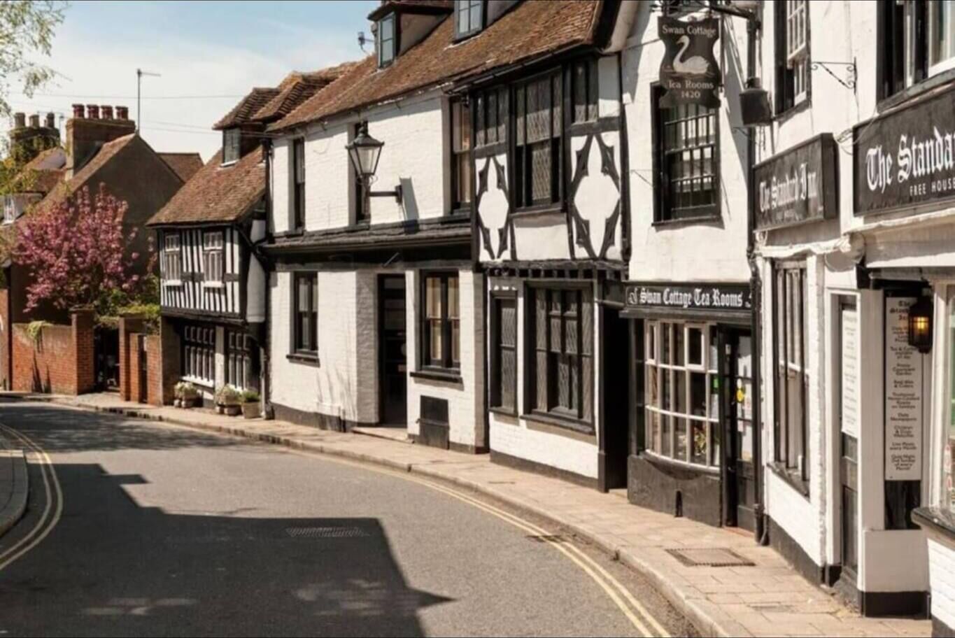 Un bâtiment traditionnel à la façade noire et blanche, avec une enseigne indiquant « Swan Cottage Tea Rooms » et une autre indiquant « The Standard Free House ».