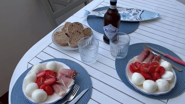 Ett runt bord med två tallrikar mat, en flaska och glas.