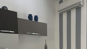 Ett litet, modernt rum med en grå soffa, ett litet bord med böcker, en dekorativ detalj på väggen och en randig vägg.