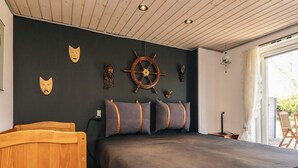 Une chambre avec un lit en bois, une literie aux couleurs sombres et des éléments de décoration murale sur le thème de la marine.