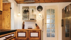 Une cuisine avec des meubles de rangement en bois, un meuble à vin intégré, une horloge et un réfrigérateur.