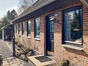 Een gebouw van baksteen met een zwarte deur, ramen en een klein portaal.