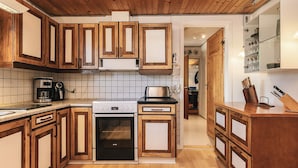 Une cuisine moderne avec des meubles en bois, un four encastré et une machine à café.