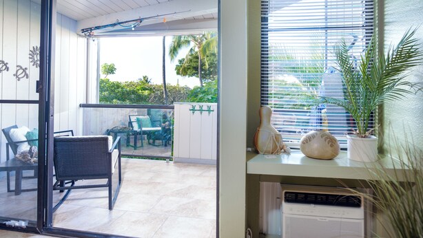 A room with a sliding glass door leading to an outdoor patio area with a table and chairs. - Kailua Bay Resort#4-204: Heart of Downtown, Walk to everything! (Kailua Kona)