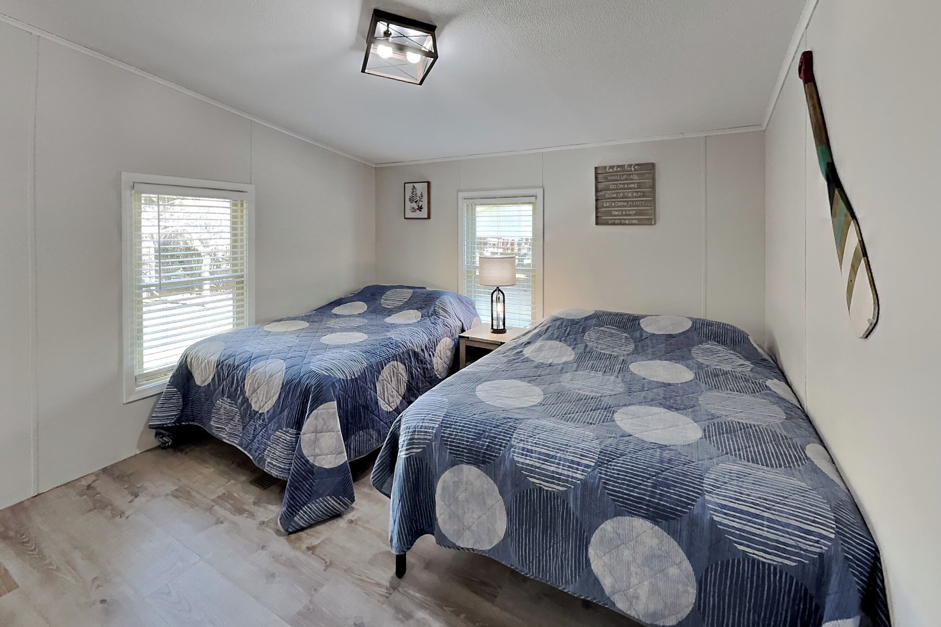 Een slaapkamer met twee bedden, houten vloeren en een plafondlamp.