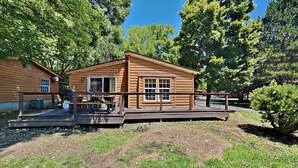 A wooden cabin with a deck, surrounded by trees. - Easy Stay w/ 2 Parking Spots | 8 ppl | IC83 (Put-in-Bay)