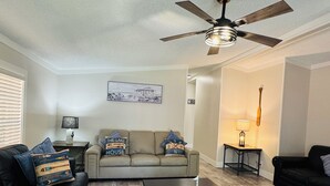 A living room with a sofa, a coffee table, a ceiling fan, and a lamp. - Easy Stay w/ 2 Parking Spots | 8 ppl | IC83 (Put-in-Bay)