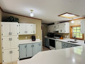 A kitchen with white cabinets, a built-in stove, a sink, and a window with a view.