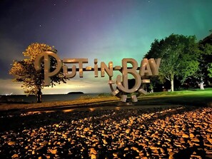Une grande enseigne lumineuse portant l’inscription « Put-in-Bay », se détachant sur un ciel nocturne parsemé d’étoiles.