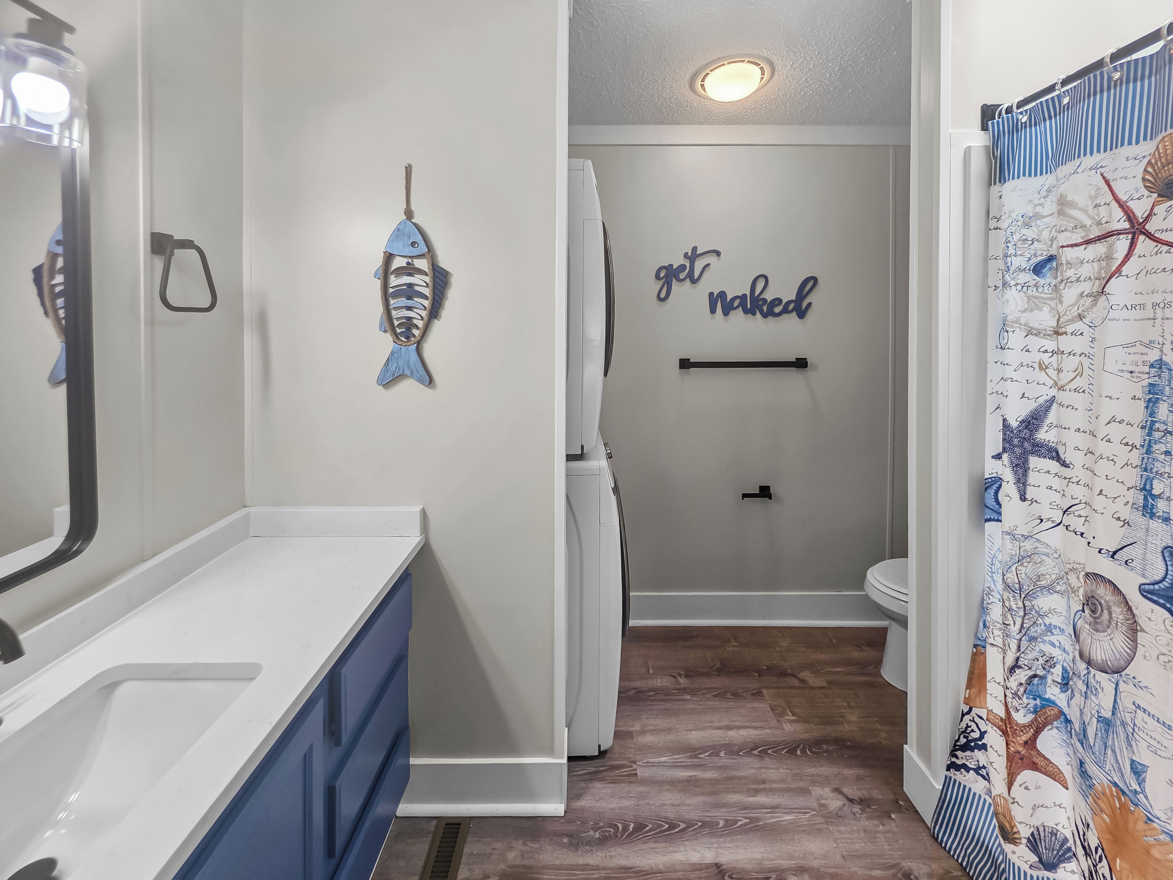 A bathroom with a white sink, a towel rack, and a wall with a nautical-themed shower curtain.