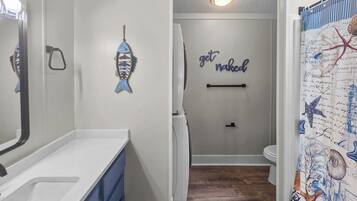 A bathroom with a white sink, a towel rack, and a wall with a nautical-themed shower curtain.