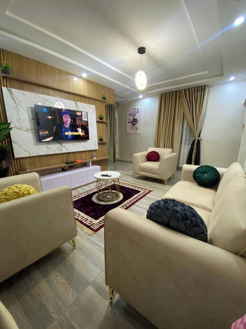 A modern living room with a marble wall, a flat-screen TV, a sofa, a coffee table, and a patterned rug.