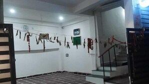 A room with a tiled floor, a staircase, and a wall with hanging decorations. - SRT Homes (Ranchi)