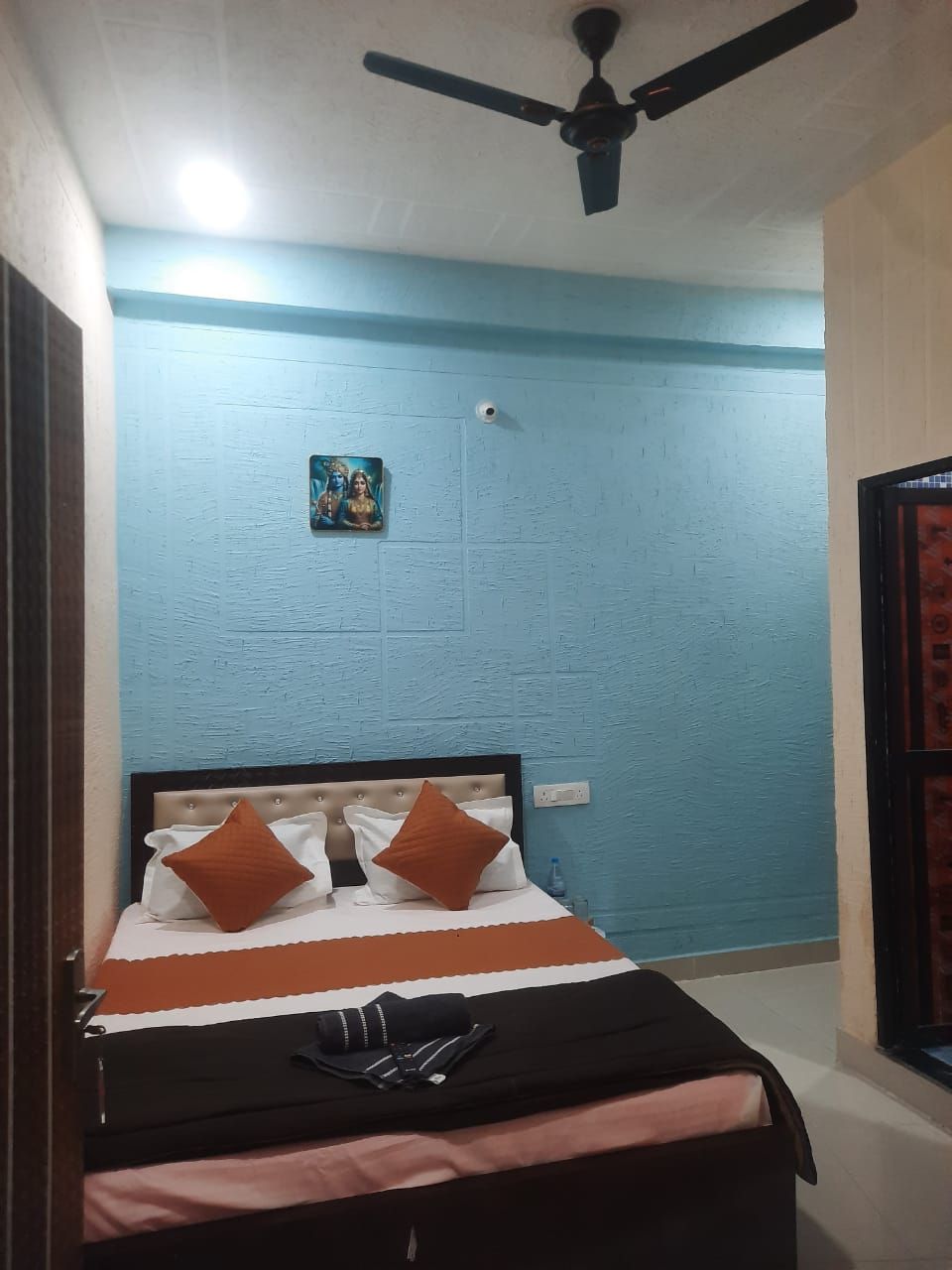 Una camera da letto con un letto, una ventola a soffitto e un quadro appeso al muro.
