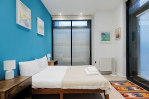 A bedroom with a bed, bedside tables, a radiator, and a window with blinds. - Tasteful 2BD Canalside Hideaway in Hackney (Greater London)