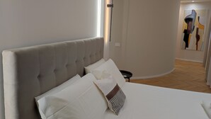 A modern hotel room with a large bed, a nightstand, and a painting on the wall. - Center Suite Cagliari (Cagliari)