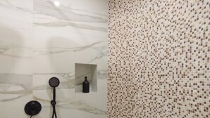A bathroom with a shower, a marble wall, and a mosaic tile wall. - Center Suite Cagliari (Cagliari)