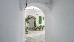 An arched doorway leading to a courtyard with potted plants and a white door. - Belvedere Apartment with Views of Vejer’s Historic Old Town (Vejer de la Frontera)