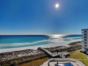 Um hotel à beira-mar com piscina, calçadão e vista para o oceano.