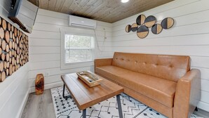 Una sala moderna con techo de madera, sofá de cuero, una mesa de centro y aire acondicionado instalado en la pared.
