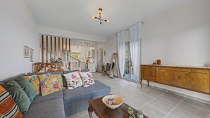 A spacious living area with a sofa, a wooden coffee table, and a dining area in the background.