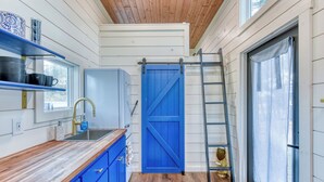 Eine Küche mit Holzausziehtisch, blauen Schränken, einem Spülbecken und einer blauen Tür im Stil eines Bauernhauses.