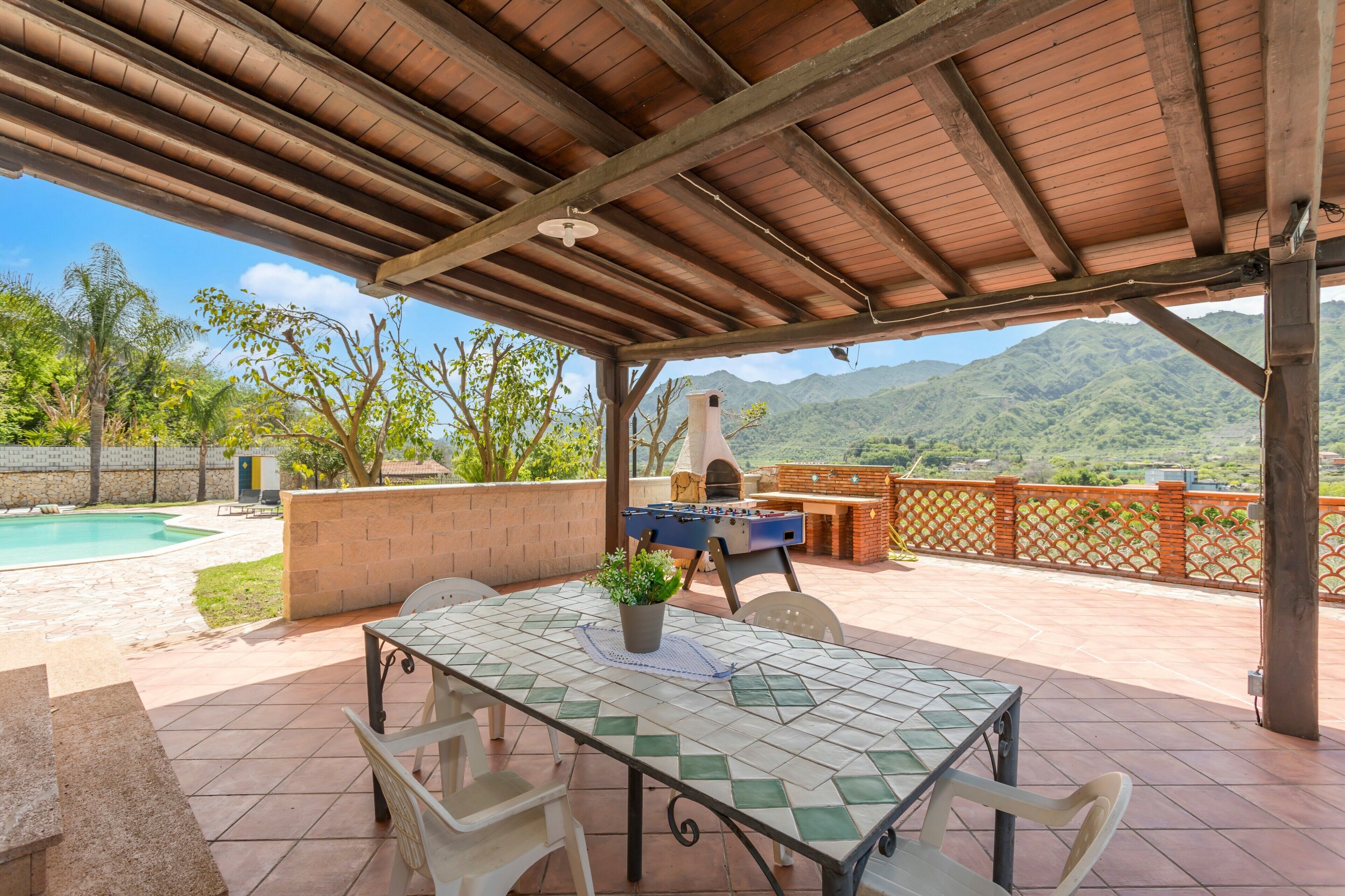 Une terrasse extérieure avec une table, des chaises, un barbecue et une vue sur les montagnes.