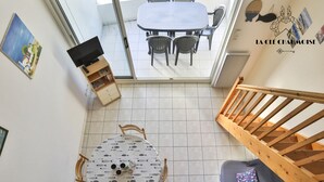 A room with a dining table, chairs, a sofa, and a staircase. - Capitainerie – Marina des Sables d’Olonne (Les Sables-d´Olonne)
