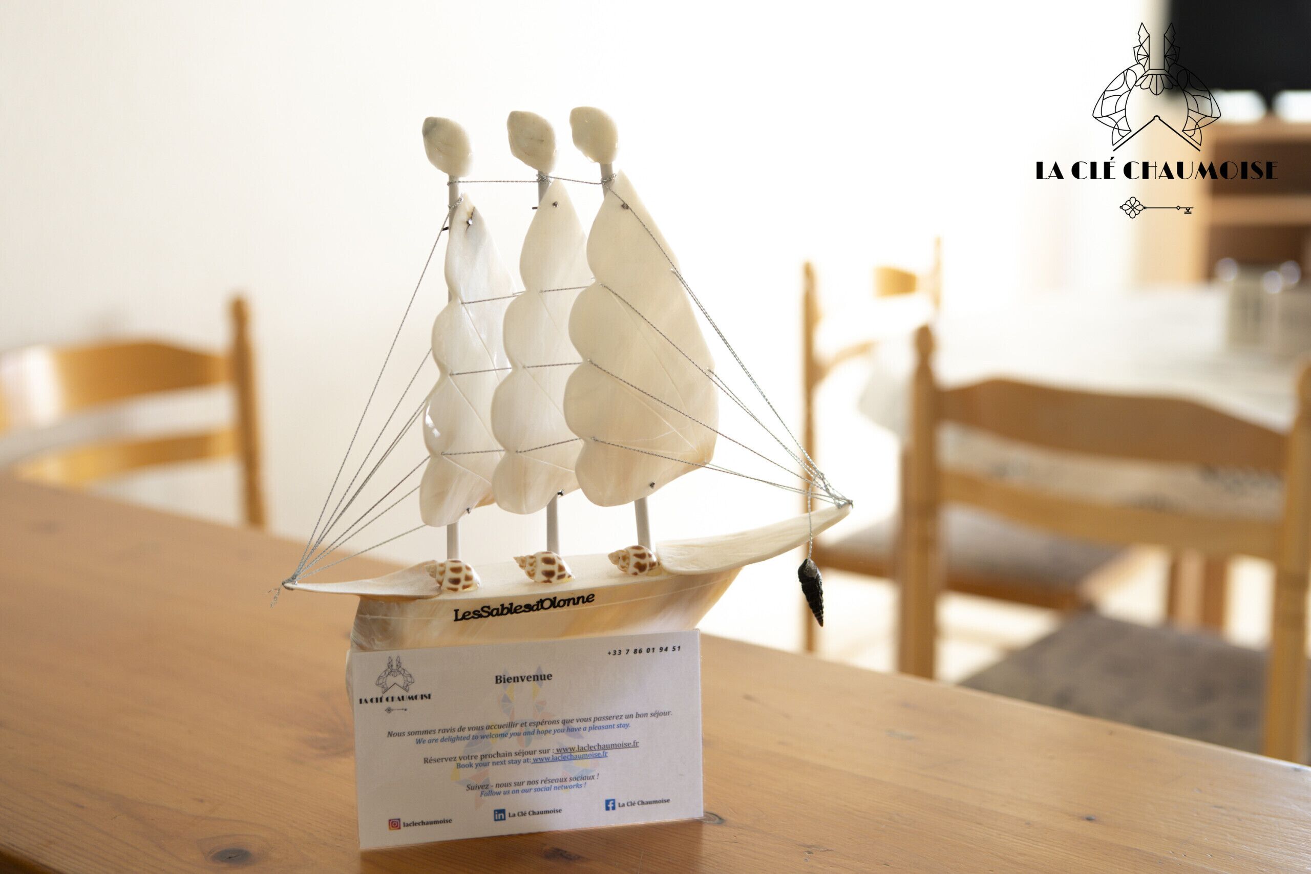 Un velero modelo sobre una mesa con una tarjeta de bienvenida debajo.