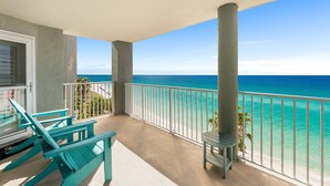 A balcony with turquoise chairs and a small table, overlooking a beach with clear blue water. - Incredible Gulf Views from Every Room | 2BR/2BA | Sleeps 6. Under new management! (Panama City Beach)
