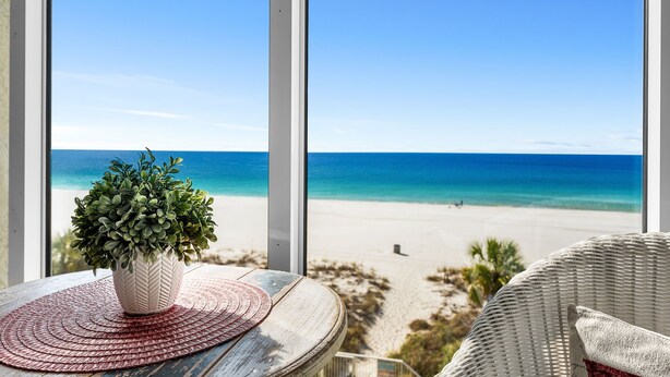 A view of a beach from a window with a potted plant on a wooden table. - Incredible Gulf Views from Every Room | 2BR/2BA | Sleeps 6. Under new management! (Panama City Beach)