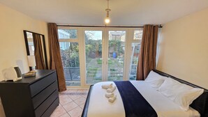 Ein Hotelzimmer mit einem Bett, einem Schminktisch, einem Spiegel und Blick ins Freie.
