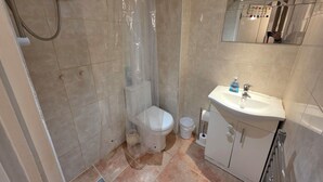 Ein Badezimmer mit Dusche, Toilette, Waschbecken und Spiegel.